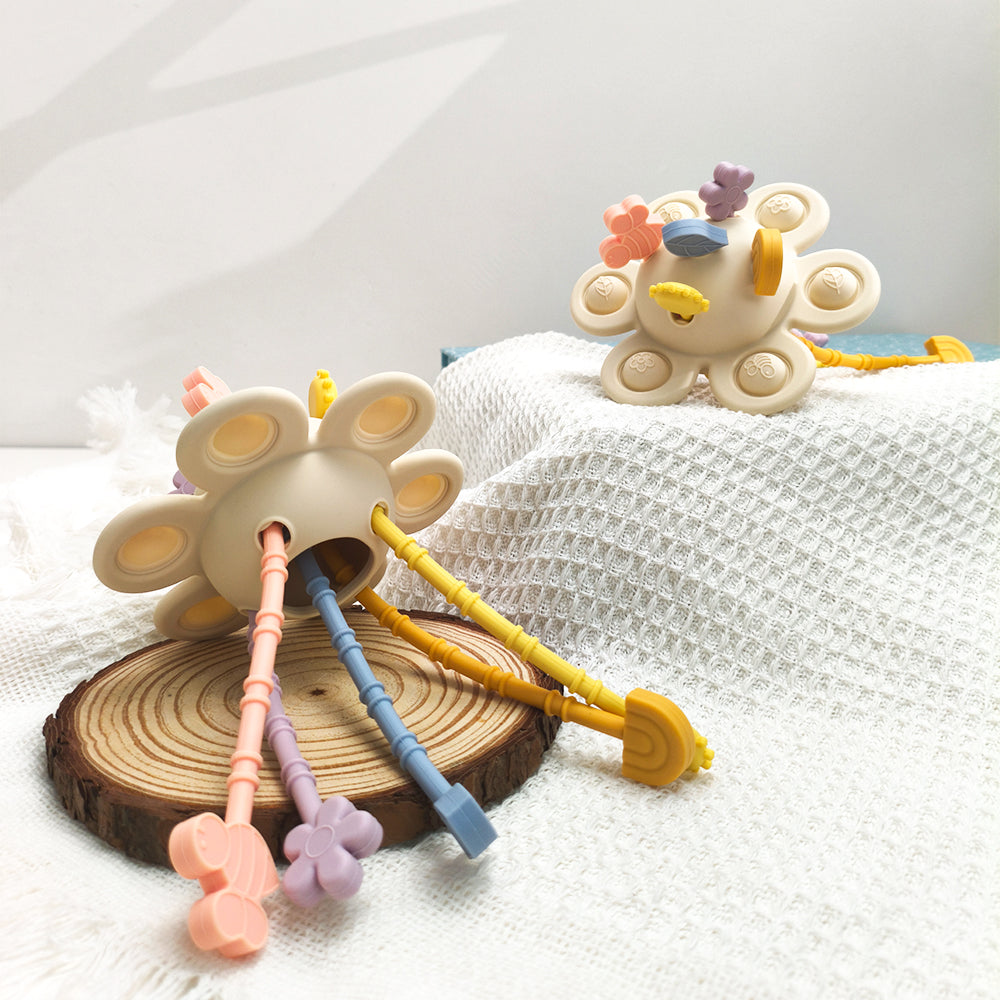 Colorful baby teething toys on a white textured surface with a wooden base.
