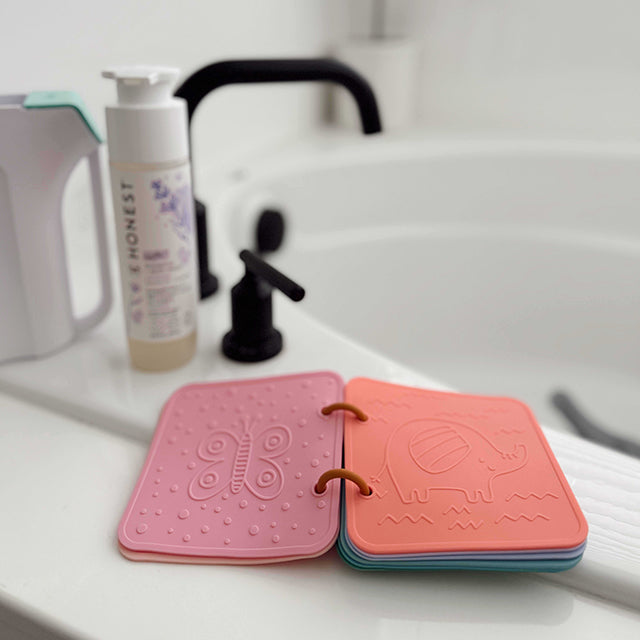 Pink and orange silicone coasters with embossed designs on a bathroom counter.