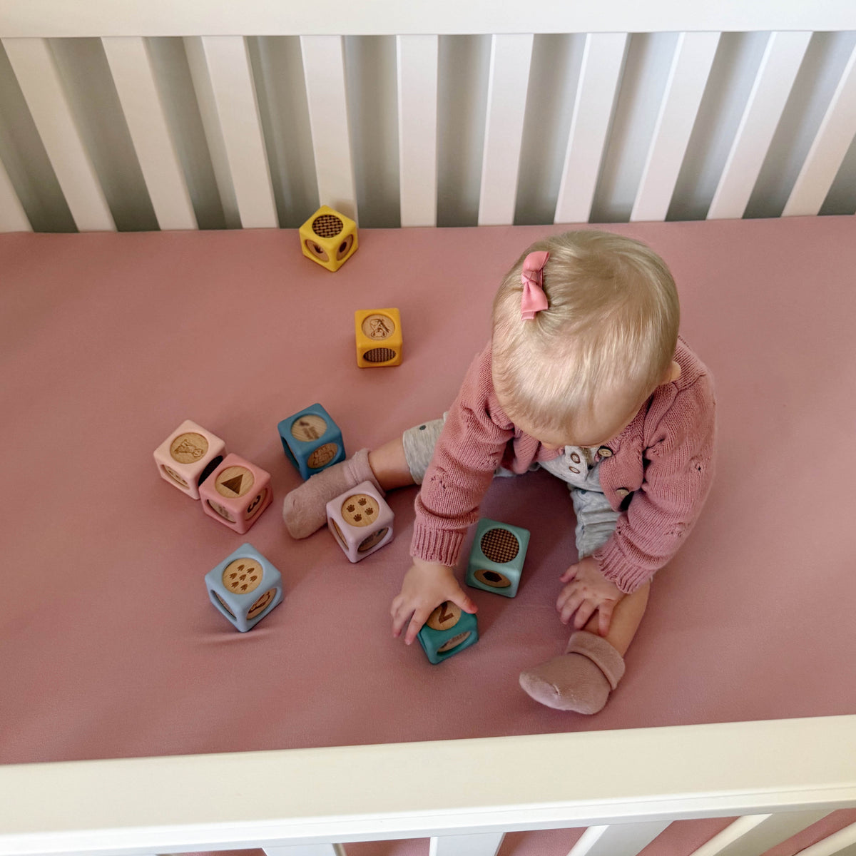 Child playing with colorful blocks on a pink surface