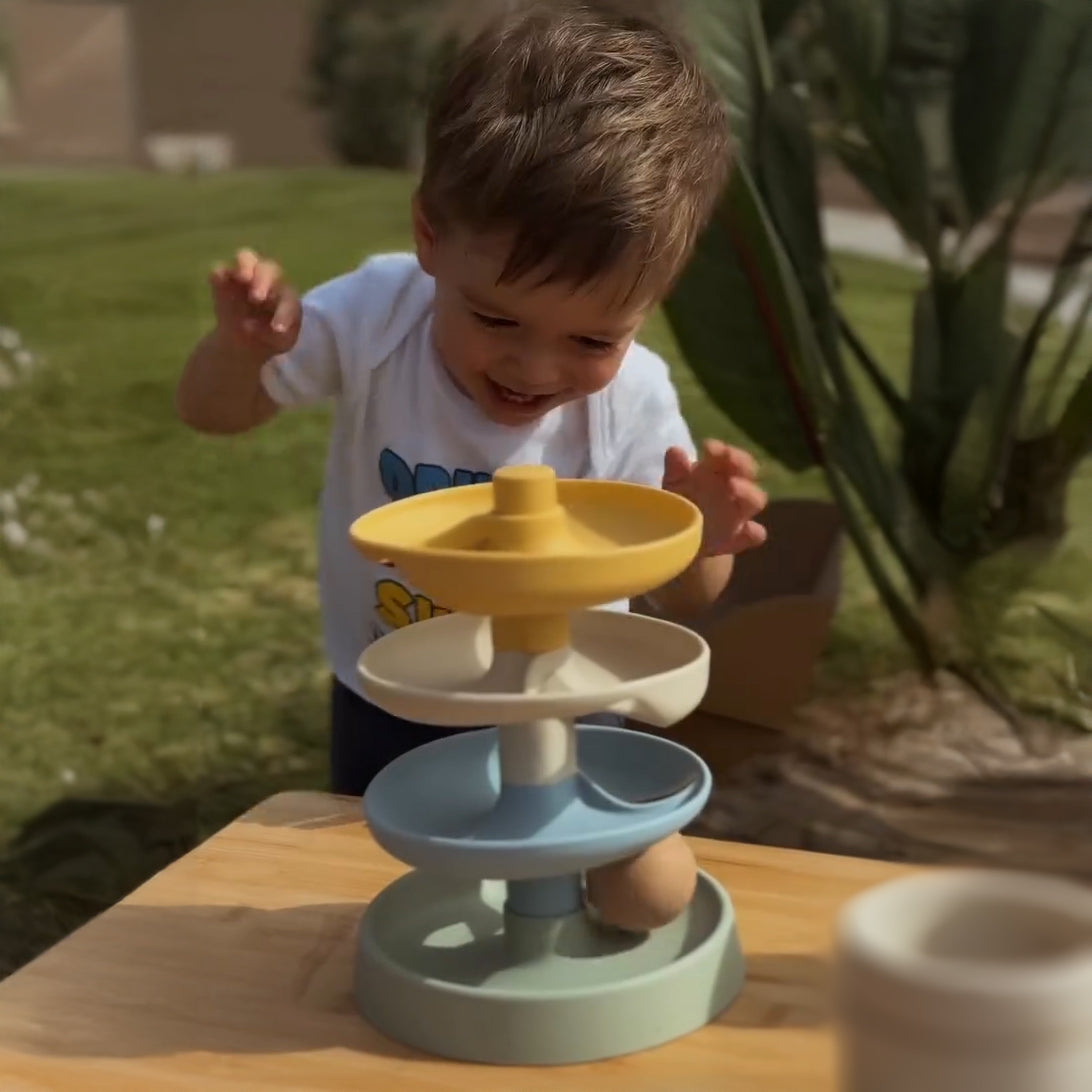 Child playing with a colorful toy on a wooden table outdoors