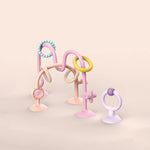 Pastel-colored baby teething toy with multiple rings on a beige background