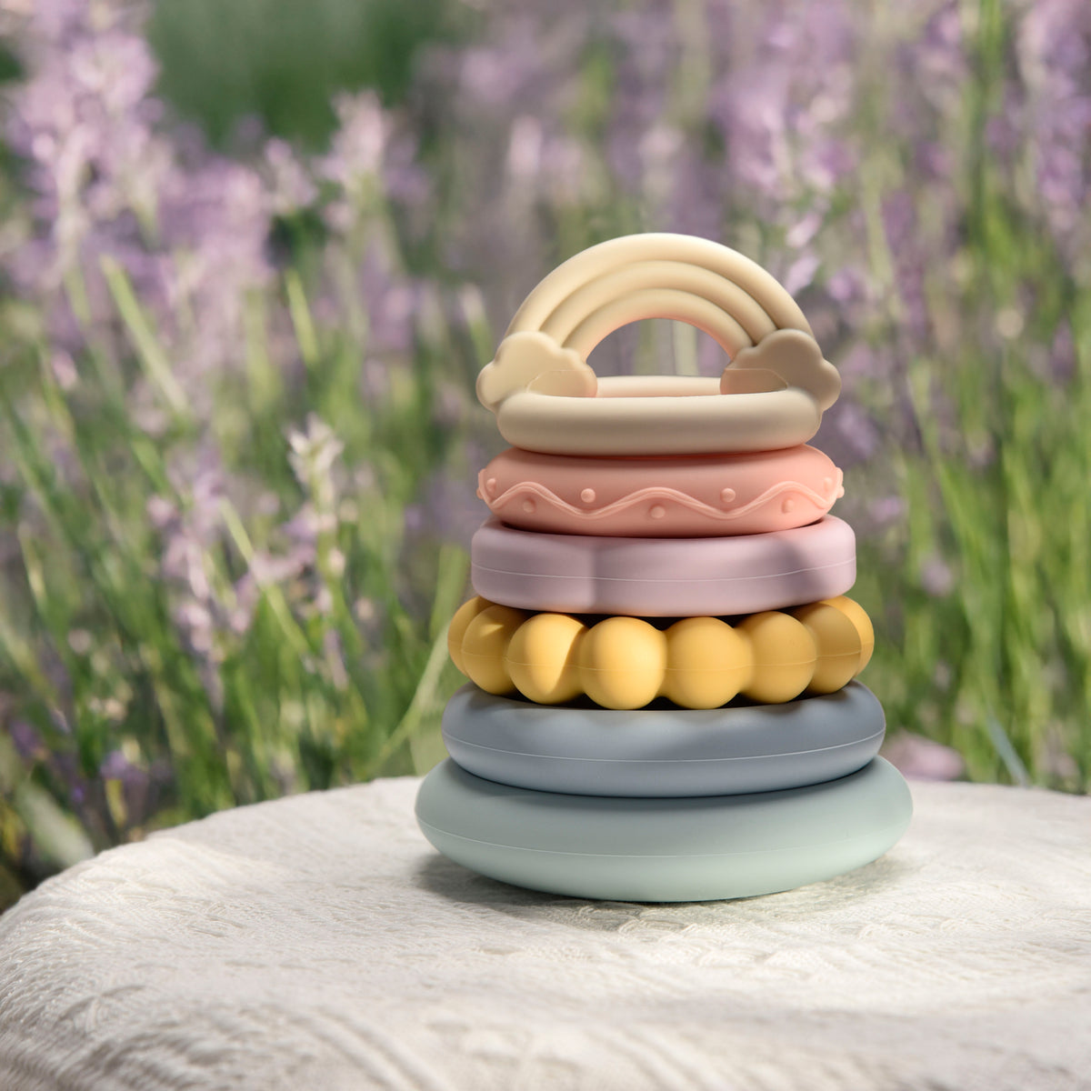 Stack of colorful baby toys with a blurred lavender background
