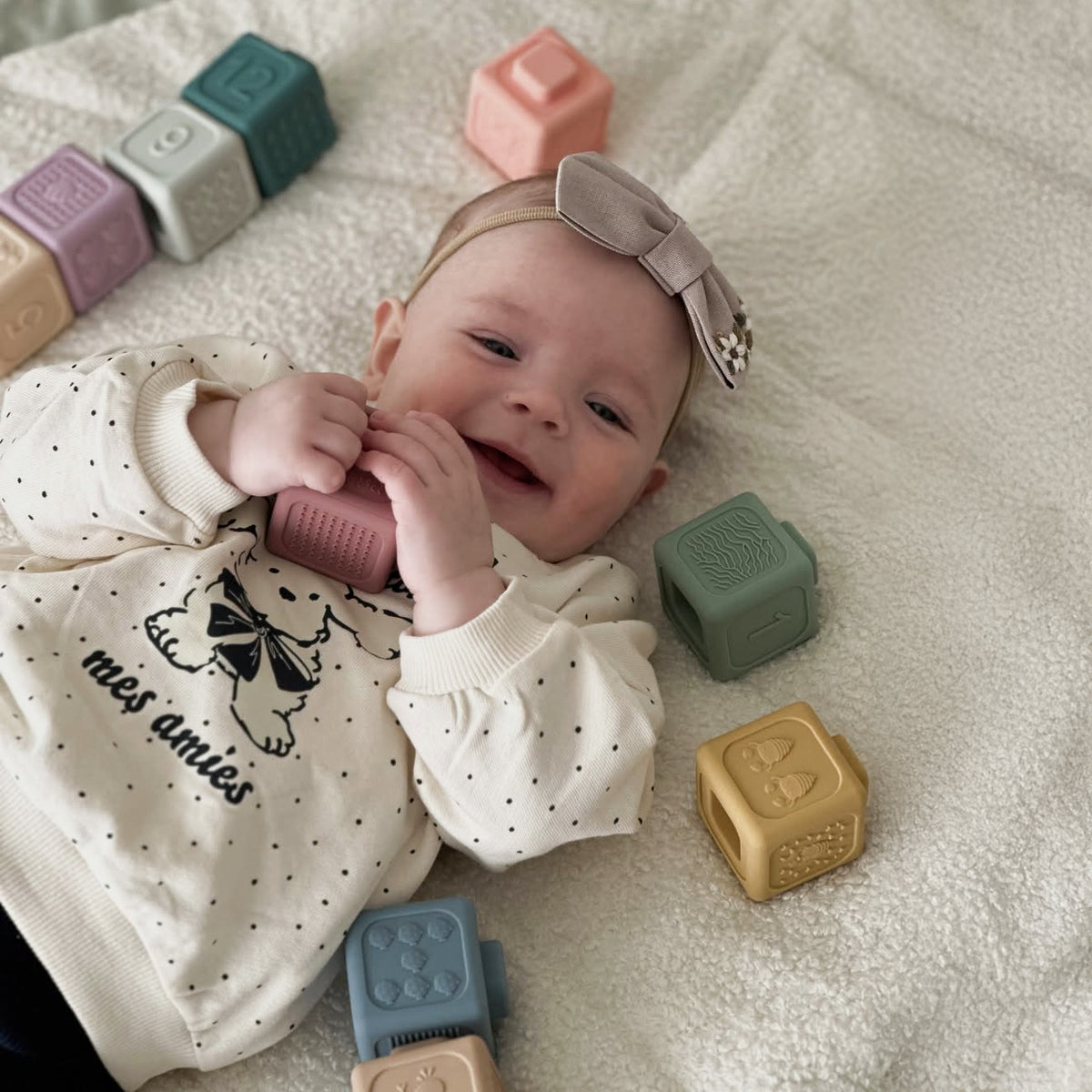 Baby lying on a blanket with colorful blocks around