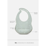 A sage green silicone baby bib with dotted details, shown with callout lines and text labels explaining its features, including adjustable neckband, super soft and lightweight, hand-in-hand design, and catcher. A size text bar is visible at the bottom.