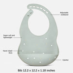 A sage green silicone baby bib with hand-inlaid dots, shown with callout labels pointing to its features, including an adjustable neckband, super soft and lightweight texture, hand-inlaid dots, and a catcher. The text at the bottom reads 'Bib 12.