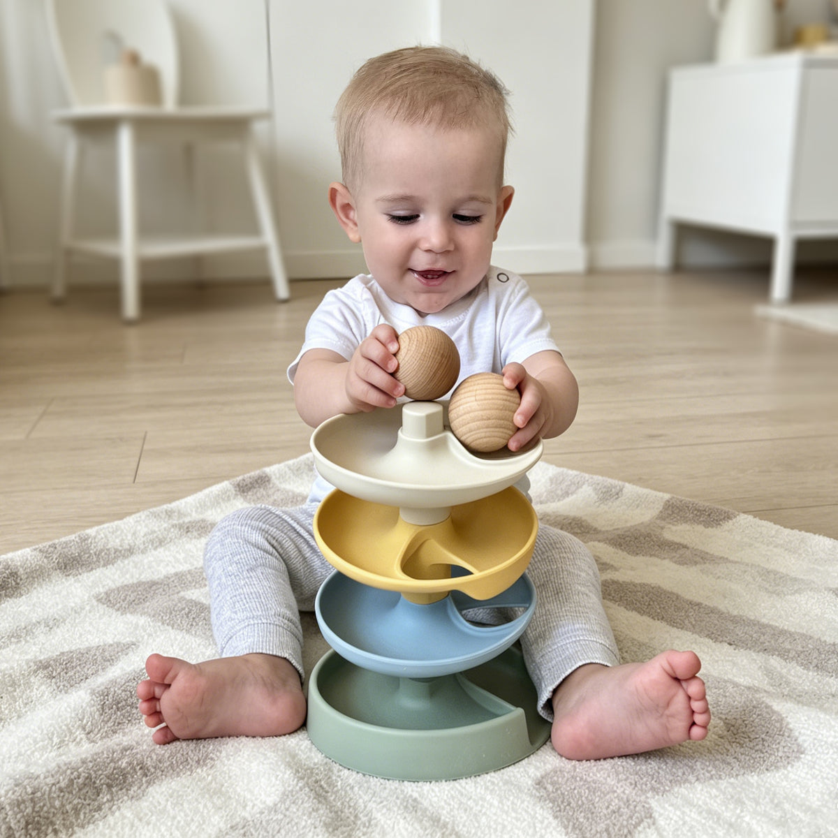 Child playing with a colorful toy pyramid on a rug