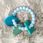 Teething toy with blue, green, and white beads on a fluffy beige surface 