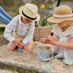 Two children playing in a sandbox with hats on