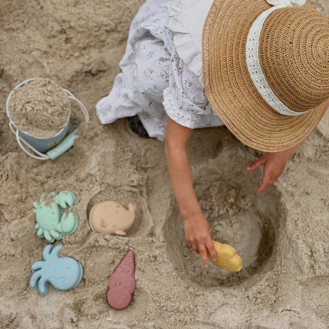 Child playing in the sand with toys on a beach