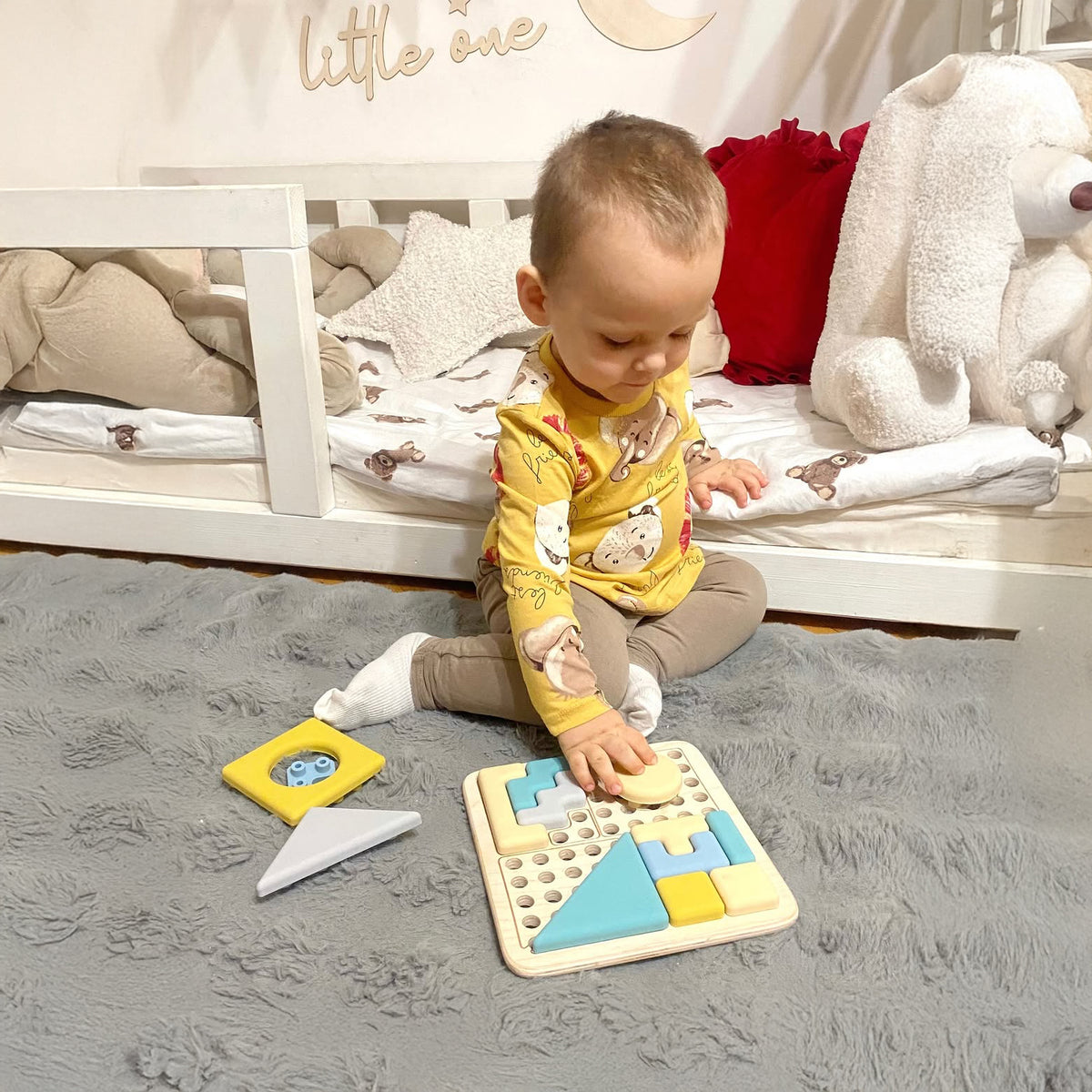 Baby playing with a geometric shape puzzle on a soft surface 