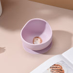 Pink bowl with a hedgehog design on a beige surface 