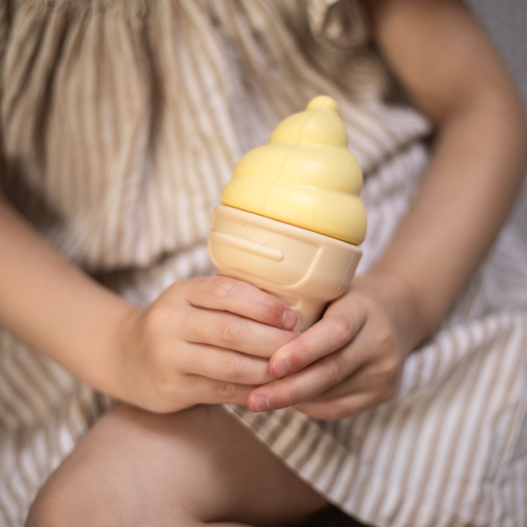 Child holding a yellow ice cream toy with a soft focus background