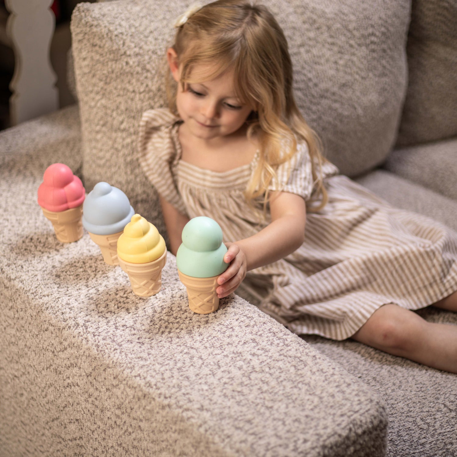 Child playing with colorful ice cream toy cones on a soft surface