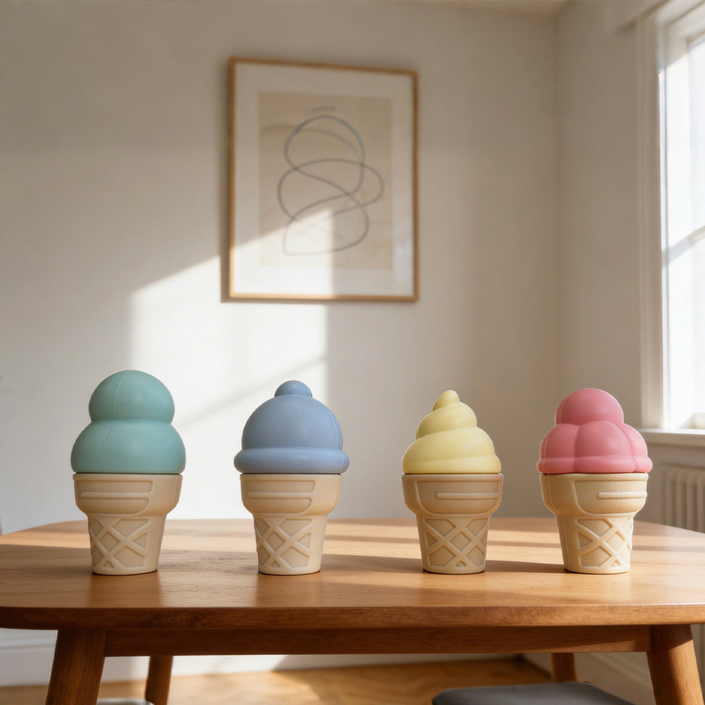 Four ceramic ice cream cone sculptures in pastel colors on a wooden table.