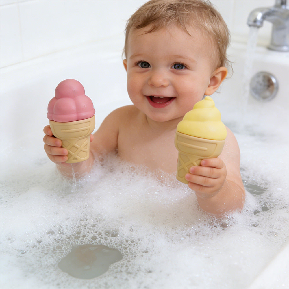 Child in a bathtub holding two ice cream-shaped toys.