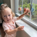 Child by a window with decorative flowers and a fan 