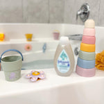 Bath time setup with a bottle, bucket, and toys on a bathtub ledge. 