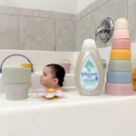 Child in a bathtub with bath toys and a bottle of shampoo or conditioner.