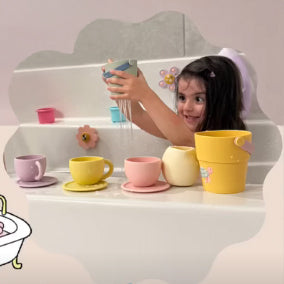 Child playing with colorful cups and saucers on a white surface.