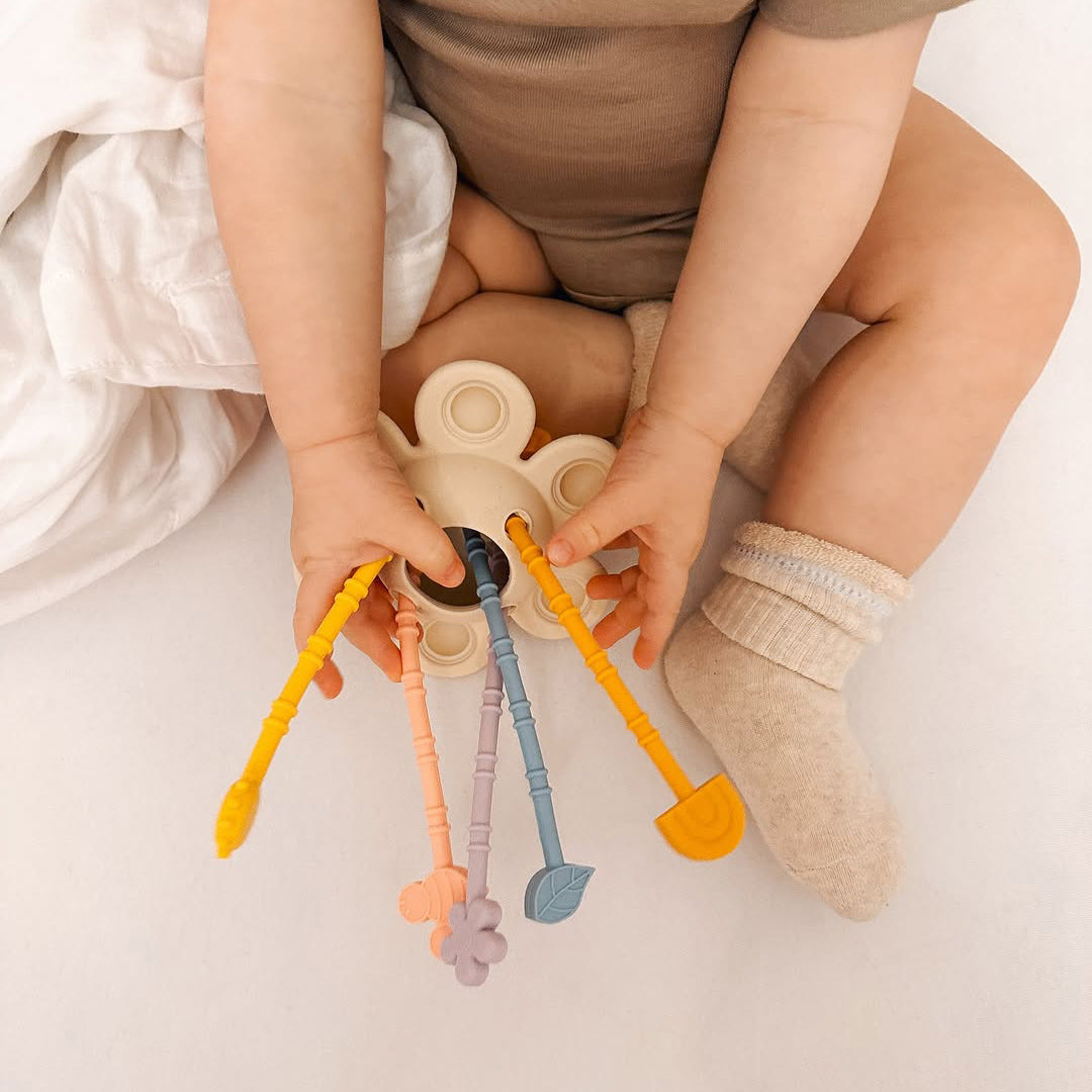 Baby playing with colorful teethers on a light background