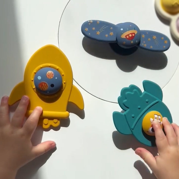 Colorful children's toys on a white surface with hands interacting with them. 