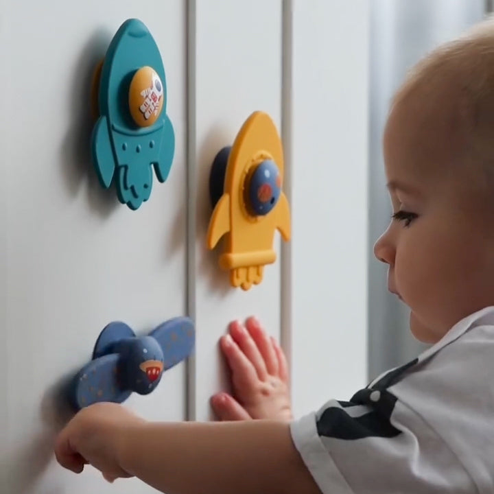 Baby interacting with colorful toy magnets on a white surface 