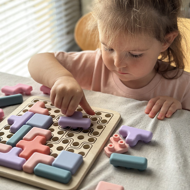 Child playing with colorful puzzle pieces on a wooden board 