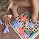 Child playing with a colorful puzzle toy on a brown surface 