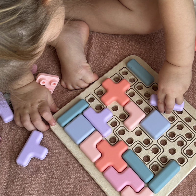 Child playing with a colorful puzzle toy on a brown surface 