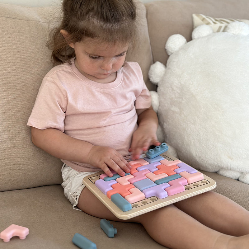 Child playing with a colorful puzzle toy on a couch 