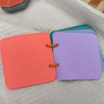 Colorful children's books with embossed designs on a textured surface 