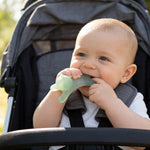 Baby sitting in a stroller with a green teething ring