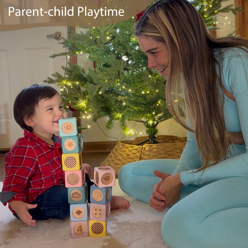 A toddler sits on a carpeted floor next to a woman, building a tower of colorful wooden blocks with numbers and shapes. A decorated Christmas tree with warm lights is in the background, and the text 'Parent-child Playtime' is visible at the top left.
