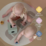 Two babies play with a wooden shape-sorting toy on a patterned circular rug, with feature callout icons on the right highlighting shape recognition, fine motor skills, and sensory touch.