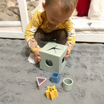 Child playing with a shape sorting toy on a carpeted floor.