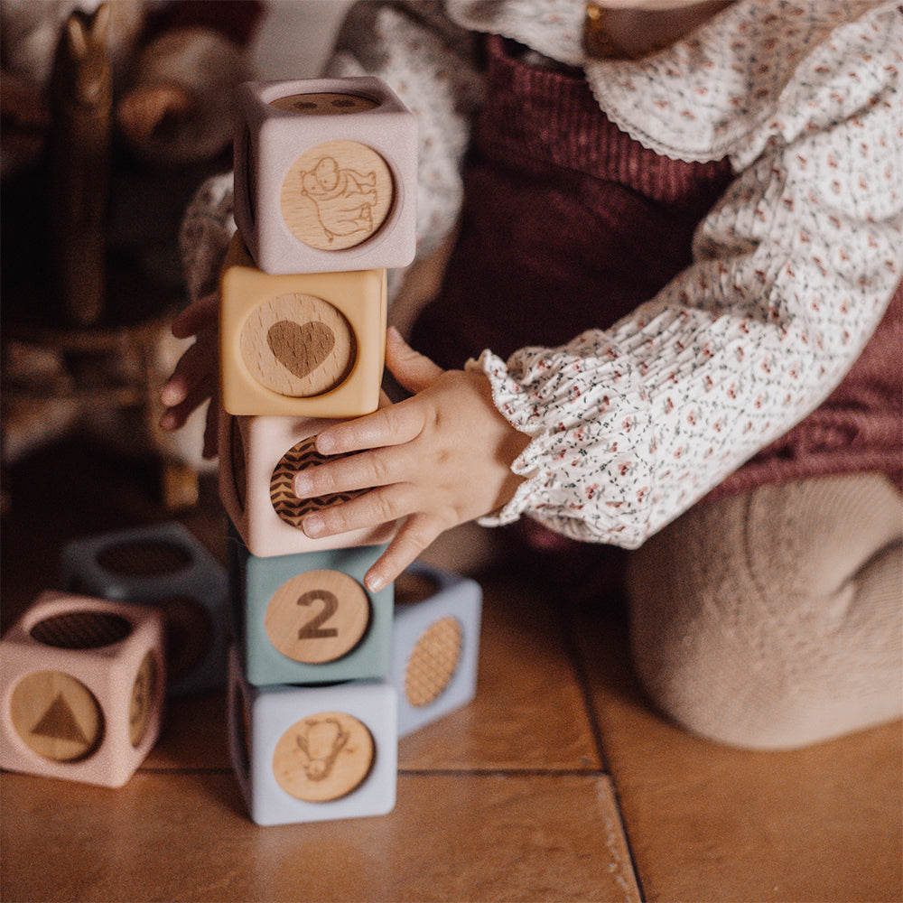 Child playing with wooden blocks on a wooden floor