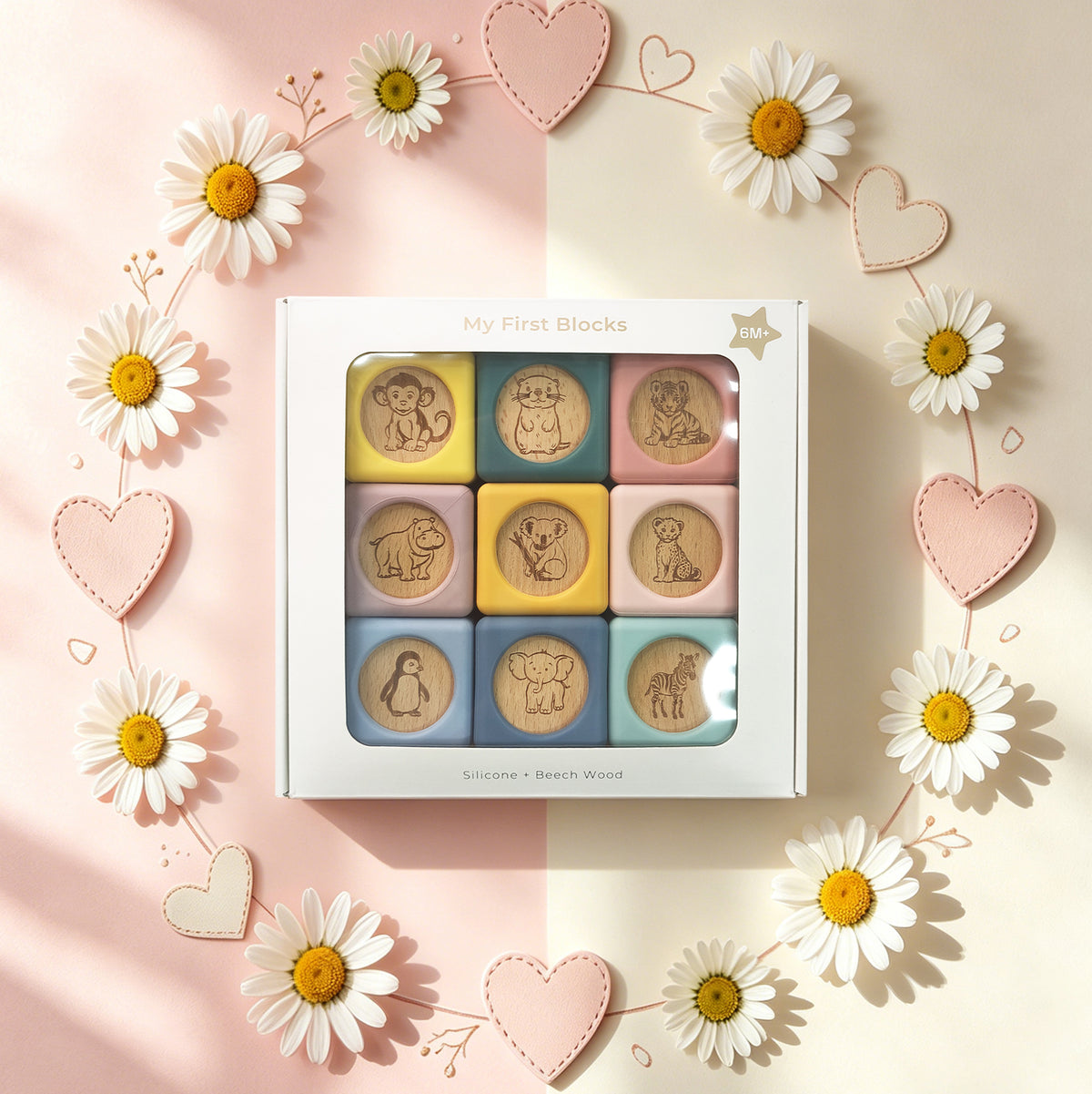 Set of wooden blocks with animal illustrations in a box, surrounded by daisies and hearts on a pink and beige background.