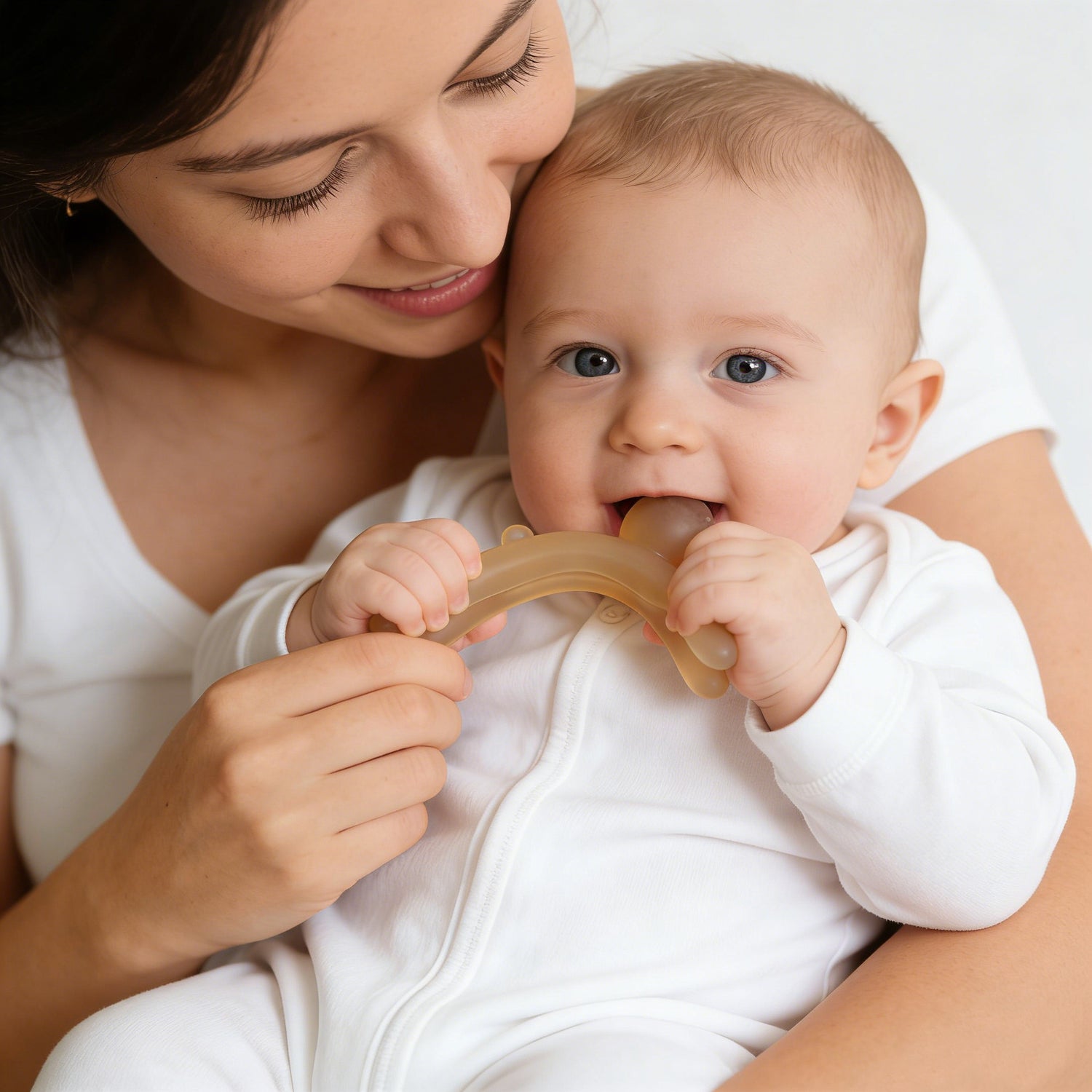 Woman holding a baby who is chewing on a teething ring.