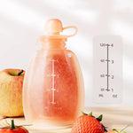 Transparent bottle with measurement markings next to an apple, strawberry, and tomato on a light background 
