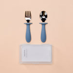 Set of silver fork and spoon with blue handles on a beige background 