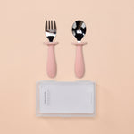Set of pink-handled fork and spoon with a clear case on a beige background 
