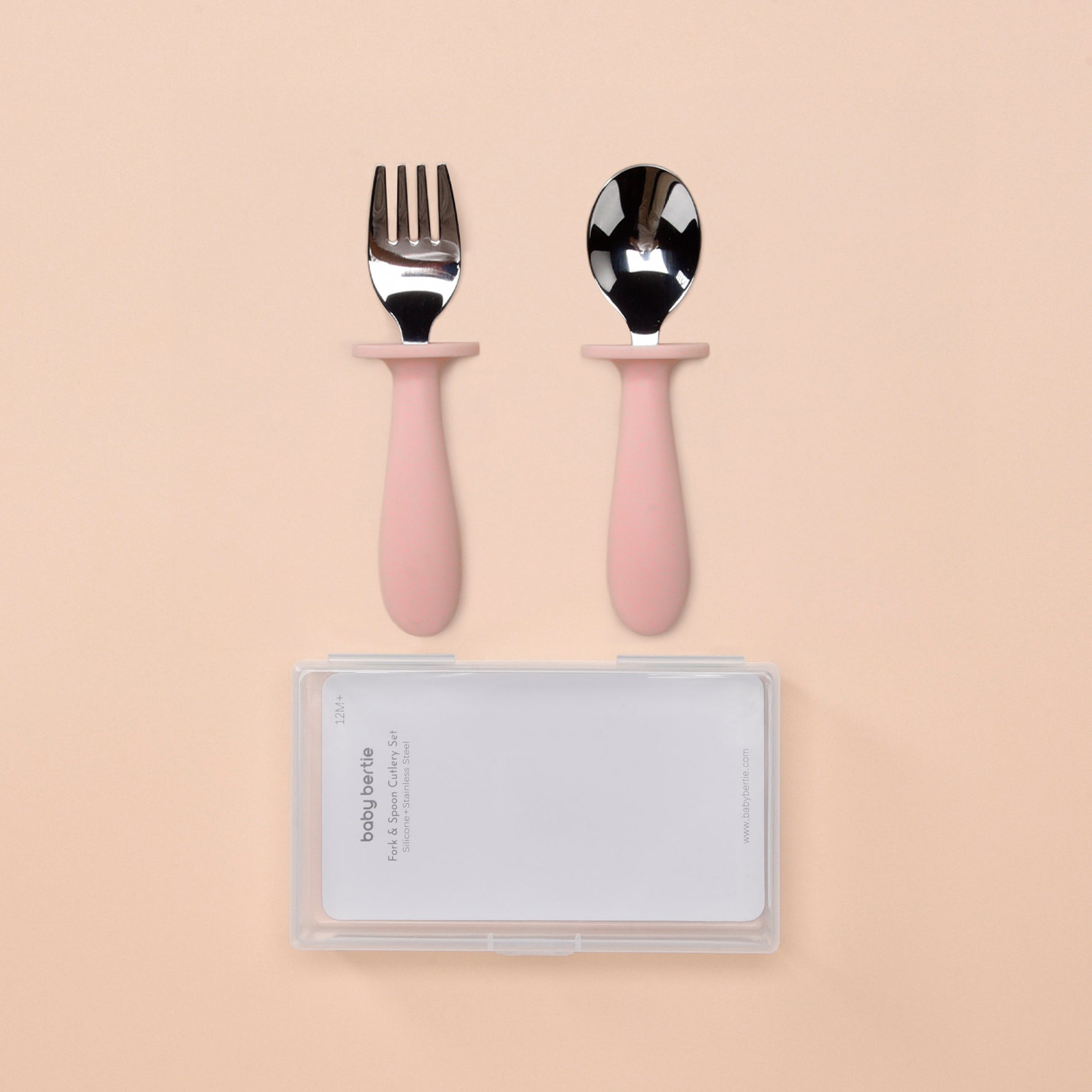 Set of pink-handled fork and spoon with a clear case on a beige background 