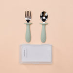 Set of silver cutlery with green handles on a beige background 
