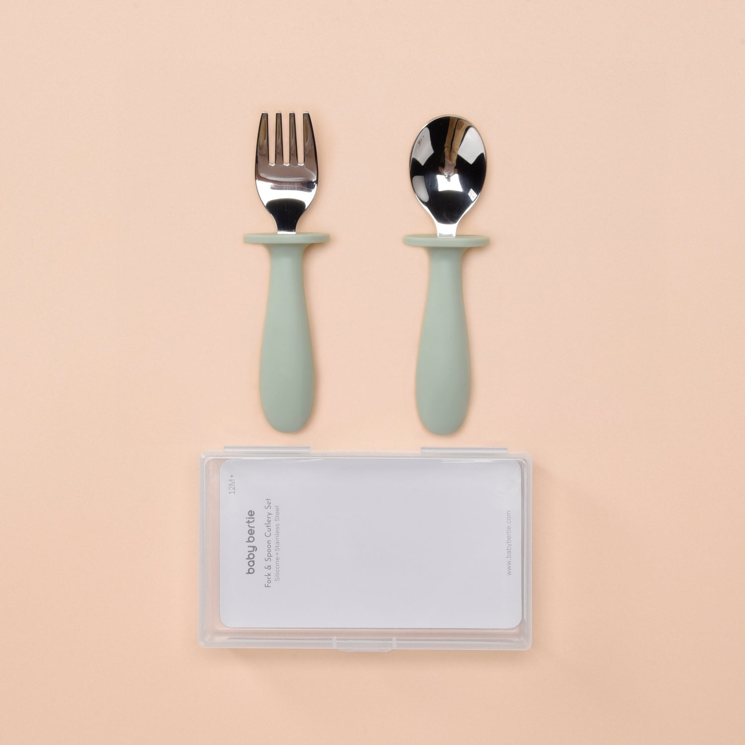 Set of silver cutlery with green handles on a beige background 