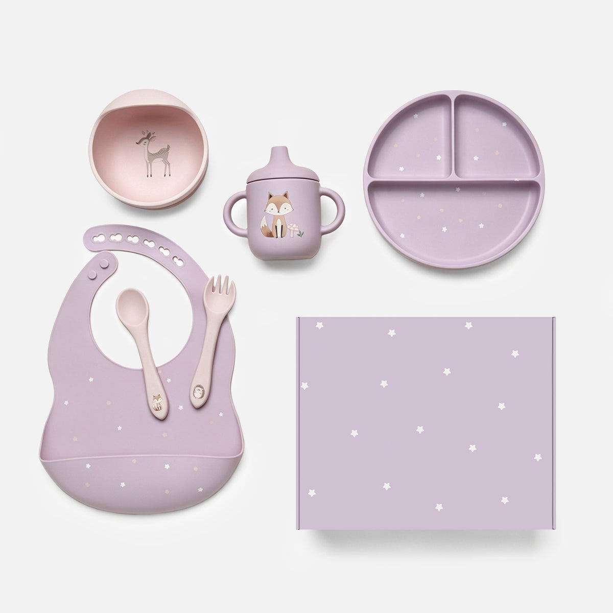 A coordinated baby feeding set arranged on a light gray background, including a lavender silicone bib with white star print, a matching plate, cup, spoon, fork, and square mat. The cup has a fox illustration, and the bowl has a deer illustration.