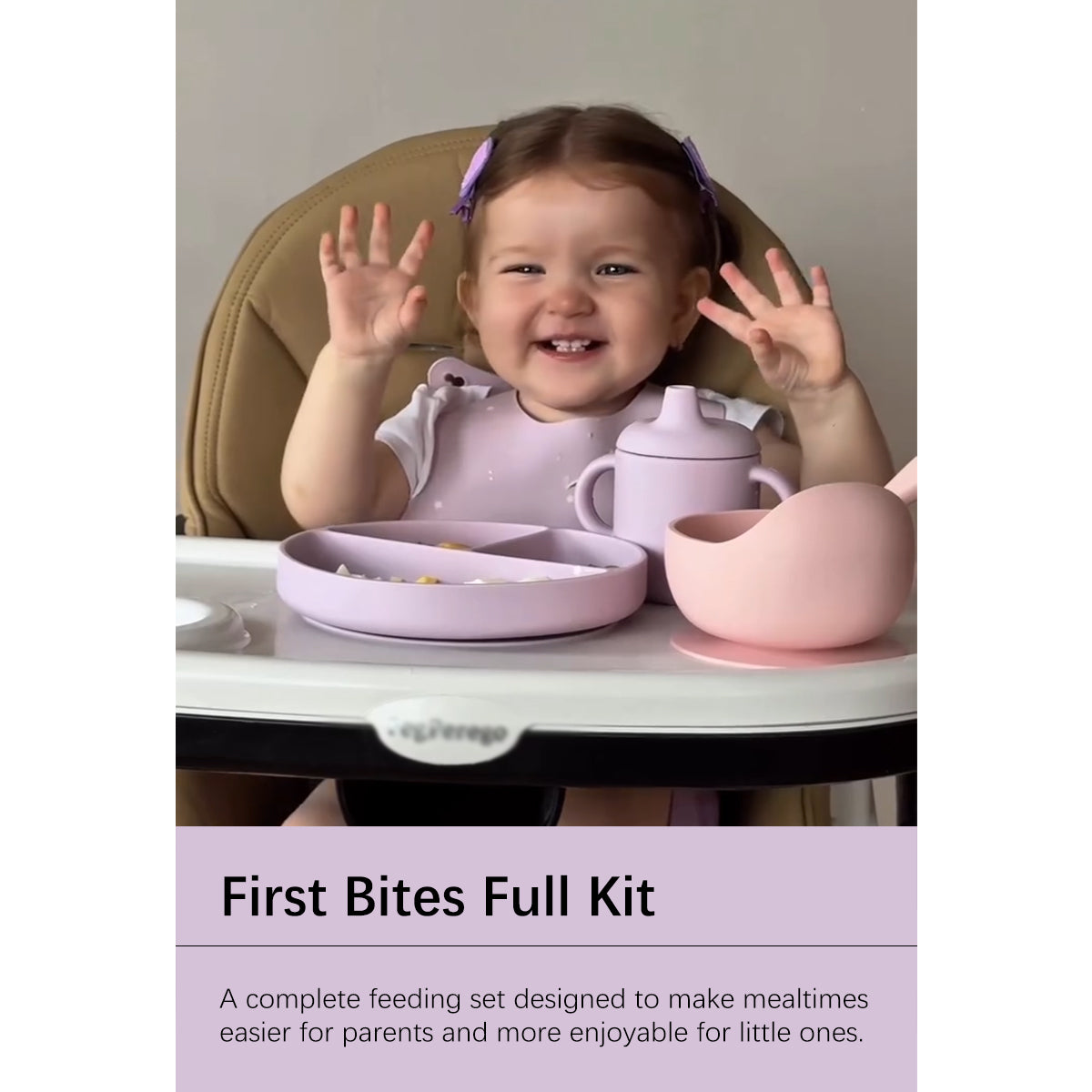 A smiling toddler in a tan high chair wearing a light purple bib, with a matching feeding set on the tray: a divided plate, sippy cup, bowl, and silicone cup. Text at the bottom reads 'First Bites Full Kit'.
