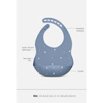 A blue baby bib with white polka dots and callout labels showing features like an adjustable neckband, hand-in-hand dots, catcher, and dimensions at the bottom.