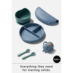 A 6-piece baby feeding set for starting solids, including a divided plate, silicone bowl, sippy cup, spoon, fork, and cover, in muted blue and teal colors with small gold and white speckles. The image is set against a light gray background with a text banner at the bottom that reads 'Everything they need for starting solids.