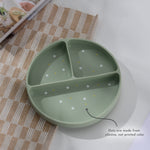 Green silicone plate with polka dot design on a checkered tablecloth 