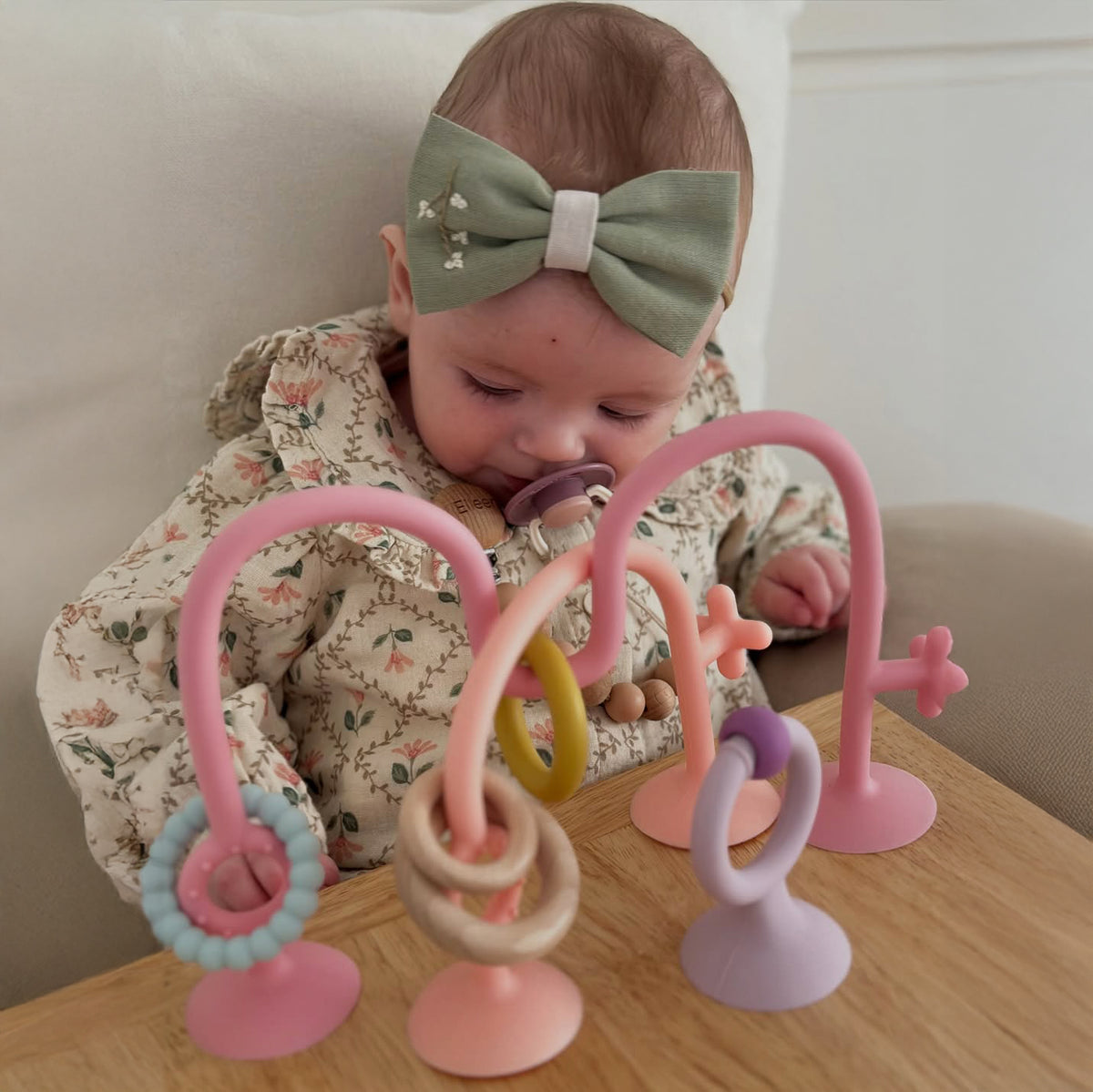 Baby playing with a colorful toy on a wooden surface 